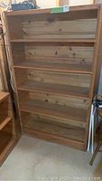 Front view of the wooden bookcase showing five fixed shelves and natural wood grain surface.