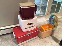 Photo showing Ravens Styrofoam cooler, Coleman chest cooler, Igloo Tag A Long cooler, orange Tupperware container, beige food storage container, and the beach-themed divided platter behind.