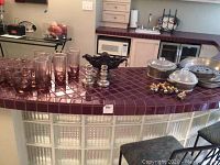 Glasses, silver plate bowl, candlestick holders, napkin rings, Guardian cookware and pan on kitchen counter