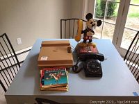 Wide shot of the lot on a table showing Mickey Mouse phone, black rotary phone, tan Fisher-Price record player, and children's record books stacked