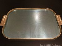 Top view of rectangular ribbed metal tray with gold handles and blue/turquoise textured surface.