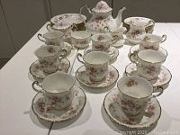 Full set arranged on table showing teapot, sugar and cream pieces, cups on saucers and stacks of plates