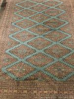 Carpet displayed flat showing central diamond lattice pattern on blue-green field