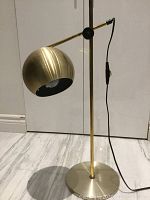 Front view of brass adjustable lamp showing round base, vertical stem and spherical shade