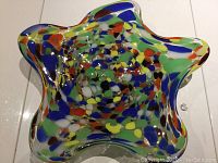 Top view of multi-coloured Murano glass charger showing star-shaped wavy edges with vibrant color spots on clear glass.