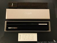 Pair of black Christofle chopsticks in white branded box with black velvet pouch and information card.