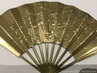 Close-up view of embossed phoenix bird detail on the brass fan