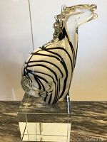 Side view of vintage Murano glass horse figurine on clear acrylic stand