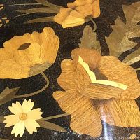 Close-up of floral marquetry showing different wood textures and colors on a lacquered surface.