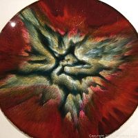 Close-up side view showing detailed enamel explosion abstract pattern with red, black, gold and pink hues.