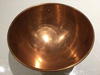 Interior view of the copper mixing bowl showing smooth reflective surface with some wear marks and scratches.