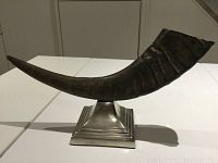 Full side view of vintage horn mounted on silver-tone stepped metal base, showing form and base details.