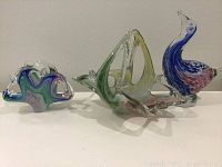 Front view of three multicoloured Murano glass art pieces on white surface