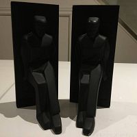 Front view of pair of black sculpted men bookends with rectangular backs, showing the pushing man design and signed details.