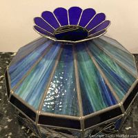 Close-up top side view showing the cobalt blue petal-like design and variegated blue-green glass panels of the pendant light shade piece.