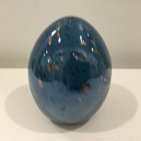 Front view of the Venetian glass egg showing deep blue color with gold flecks and glossy surface.
