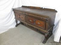 Front angled view of large walnut burl buffet server showing top surface, drawers with carved panels, and ornate carved wooden legs.