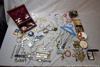 Full view of large vintage jewelry lot spread on cloth showing assorted necklaces, bracelets, watches, trinket boxes and rosary beads