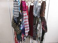 Scarf assortment hanging on metal ring hangers, showing varied patterns including stripes, animal prints, and geometric designs.