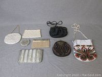 Eight assorted beaded and pearled handbags arranged side by side on a flat surface.