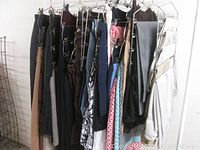Side view of assorted ladies skirts, capris, and denim pants hanging on metal hangers showing diverse colors and patterns