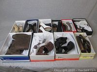 Overview of all 10 pairs of shoes in their boxes on a grey surface, showing variety in style, color, and material.