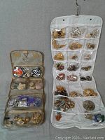 Photo showing two fabric holders with multiple compartments containing an assortment of pins and brooches. Various colors and metal finishes visible.
