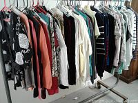 Wide shot of a clothing rack displaying assorted ladies tops including blouses, knit tops, sweatshirts, and sweaters all size 6/small