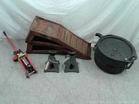 Photo showing full lot including auto ramps, floor jack, jack stands, and oil drain containers on gray floor with white backdrop