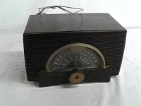 Front view of the dark brown General Electric console radio showing semicircular AM/FM tuning dial and tuning knob.