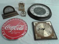 Full view of all clocks and thermometers including Coca-Cola red thermometer, round wall clock, square clock, mantel clocks, and desktop clocks.