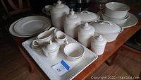 Overview of all pieces on table including rectangular tray, canisters, covered dish, bowls, creamer, sugar bowl, and gravy server