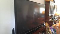 Full front view of the 72" black Mitsubishi DLP television on wooden stand