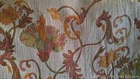 Close-up of wool blanket fabric showing colorful detailed floral and vine design and wool texture.
