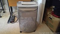 Front view of silver mesh basket shredder with shredded paper inside.
