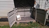 Open taupe outdoor storage bin showing inside space and white plastic bin inside