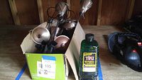 Box containing 8 copper and wrought iron tiki torches and green bottle of Tiki torch fuel