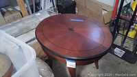 Unwrapped oval table top showing wood inlay pattern and tapered legs