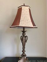 Photo of one table lamp showing bronze-colored ornamental base and multi-tone fabric lampshade with embroidered swirls