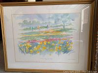 Framed pastel print of a meadow with flowers and three figures walking, in a gold frame.