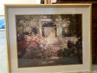 Framed print showing a garden door with surrounding flowers and greenery in a gold frame.