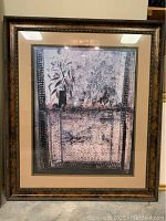 Photo of a large fruit and floral print on a table, housed in a gold-colored ornate frame with a beige matte border.