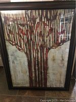 Framed print art showing red bird silhouettes perched on abstract tree branches against a muted background, in a brown wooden frame.