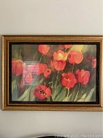 Framed orange poppy flower print hanging on wall showing entire artwork and frame.