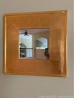 Front view of a 27 inch square wall mirror with a gold frame showing reflective surface and surroundings