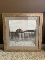 Front view of a 23-inch square sepia beach deck print in a textured gold frame with matting around the image.