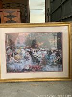 Framed print showing an outdoor lunch scene with multiple ladies, detailed and colorful, in gold frame.