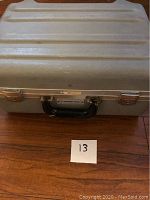 Closed gray heavy duty tool case with metal trim and black handle, labeled with number 13.