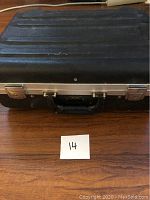 Closed black rectangular heavy duty tool case shown from front, featuring two silver metal latches and a central lock missing key.
