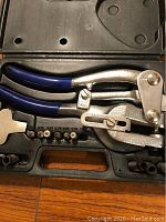 Whitney punch tool with blue grips and attachments arranged in a black molded case viewed from the top